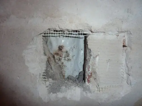 Freigelegtes Rohr in einer beschädigten Wand